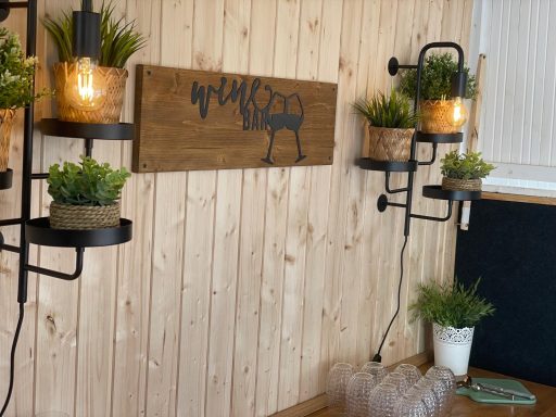 Holzwand mit Pflanzen in Körben und dekorativer Beleuchtung.