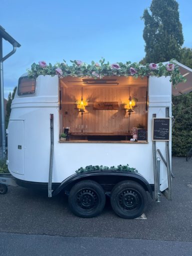 Ein dekorierter mobiler Verkaufsstand mit Blumen und warmem Licht.