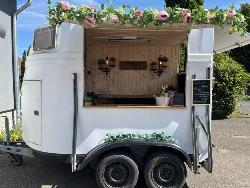 Ein weißer Food-Truck mit Blumenornamenten und Holzverkleidung.