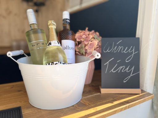 Kühler mit Weinflaschen und einer Kreidetafel mit der Aufschrift "Wine Tasting".