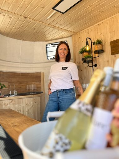 Frau steht in einer schicken Holzbar mit Getränken im Vordergrund.