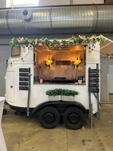 Ein mobiler Verkaufsstand in Weiß mit Blumen und einem Holzinneren.