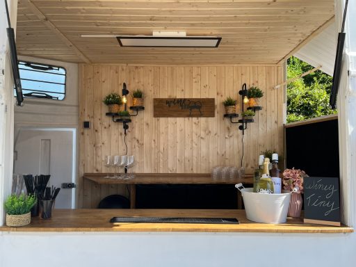 Holzvertäfelter Imbissstand mit Getränken, Gläsern und Pflanzen dekoriert.